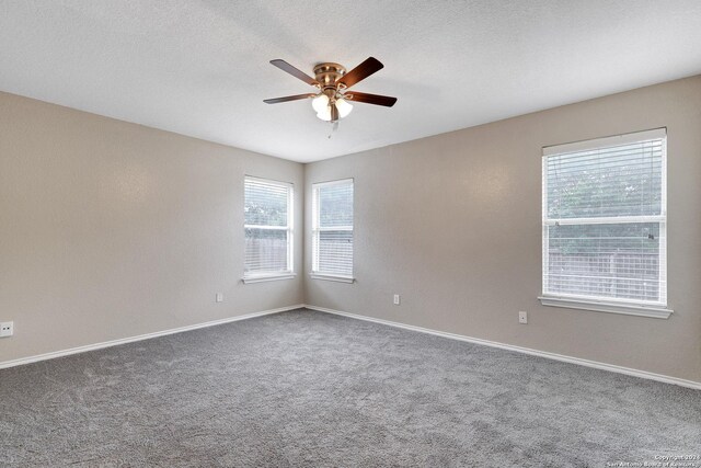 carpeted empty room with ceiling fan and a textured ceiling