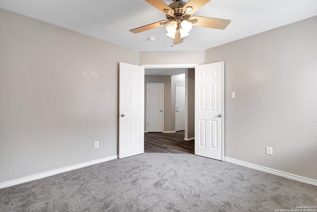 empty room featuring ceiling fan and dark carpet