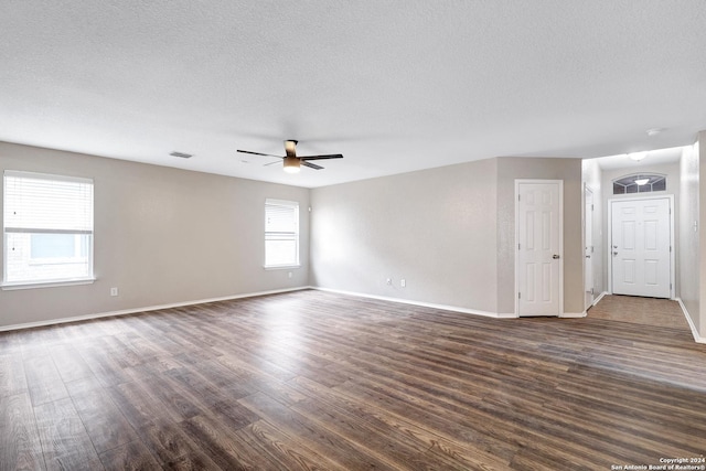 spare room featuring dark wood-style floors, visible vents, a ceiling fan, a textured ceiling, and baseboards