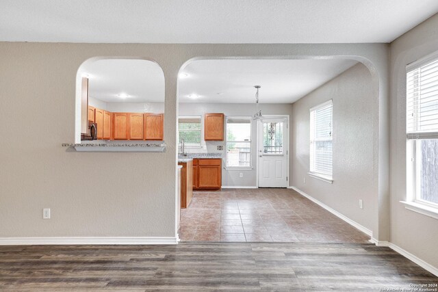 kitchen with wood-type flooring, hanging light fixtures, and a healthy amount of sunlight