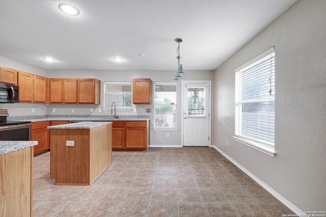 kitchen with light tile patterned flooring, sink, decorative light fixtures, range, and a kitchen island