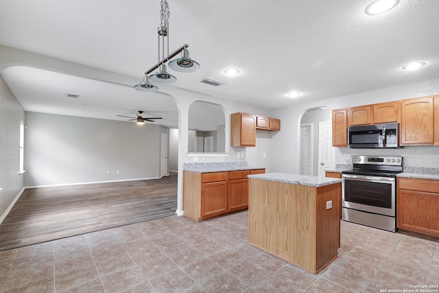 kitchen featuring stainless steel appliances, light wood-type flooring, pendant lighting, a kitchen island, and ceiling fan