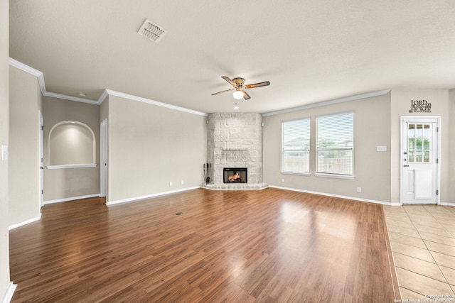 unfurnished living room featuring baseboards, visible vents, a ceiling fan, wood finished floors, and a stone fireplace