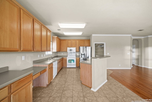 kitchen featuring arched walkways, white appliances, a sink, ornamental molding, and dark countertops