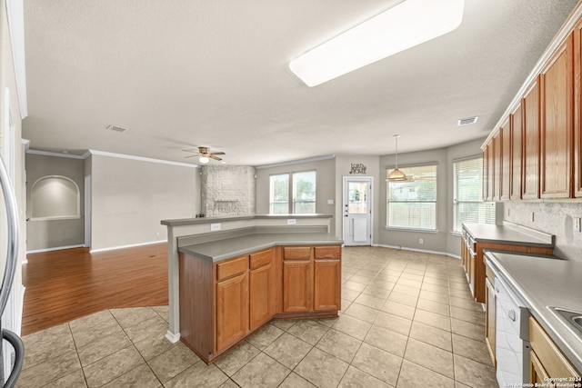 kitchen with brown cabinets, light tile patterned floors, visible vents, and open floor plan