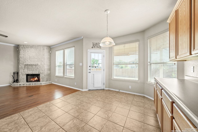 unfurnished living room with ornamental molding, a fireplace, baseboards, and light tile patterned floors