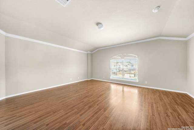 empty room featuring lofted ceiling, wood finished floors, and baseboards