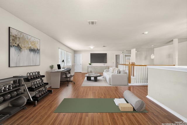 workout area with wood finished floors, visible vents, and baseboards