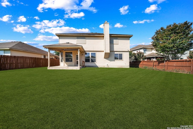 back of property featuring a patio, a yard, a chimney, and a fenced backyard