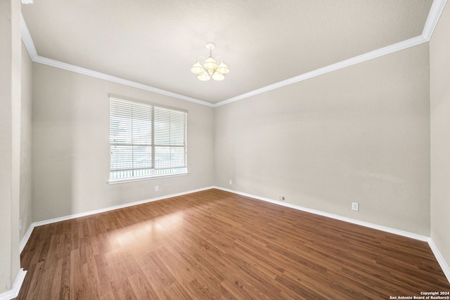 unfurnished room featuring crown molding, a notable chandelier, baseboards, and wood finished floors