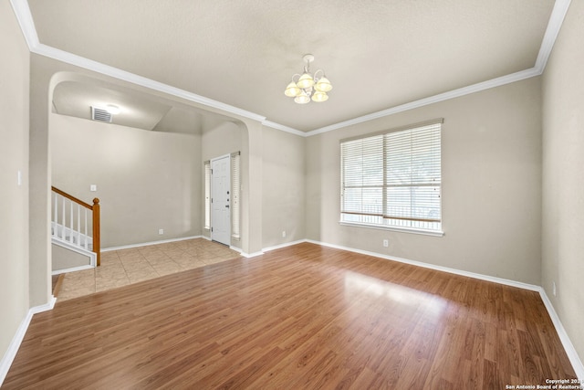 spare room with a notable chandelier, visible vents, light wood-style flooring, baseboards, and stairs