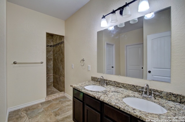 bathroom with tiled shower, dual vanity, and tile patterned floors