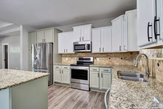 kitchen with decorative backsplash, white cabinets, appliances with stainless steel finishes, light hardwood / wood-style floors, and sink