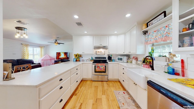 kitchen with appliances with stainless steel finishes, light hardwood / wood-style flooring, ceiling fan, kitchen peninsula, and white cabinets