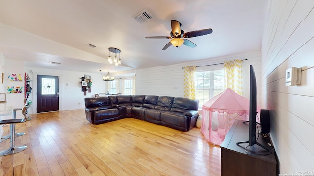 living room featuring light hardwood / wood-style flooring, vaulted ceiling, and ceiling fan with notable chandelier