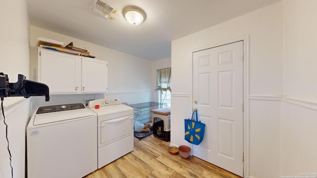 clothes washing area featuring light hardwood / wood-style flooring, washer and clothes dryer, and cabinets