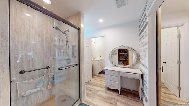 bathroom with hardwood / wood-style flooring, vanity, and a shower with shower door