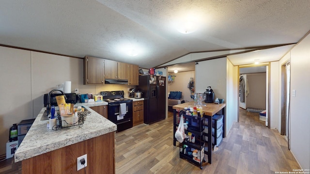 kitchen with lofted ceiling, ventilation hood, hardwood / wood-style flooring, and black appliances