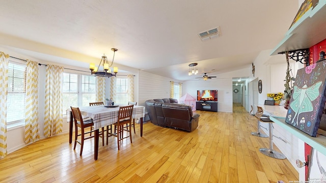 dining space with light hardwood / wood-style floors and ceiling fan with notable chandelier