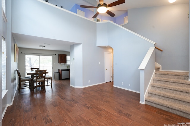 living room featuring ceiling fan, a towering ceiling, and wood-type flooring