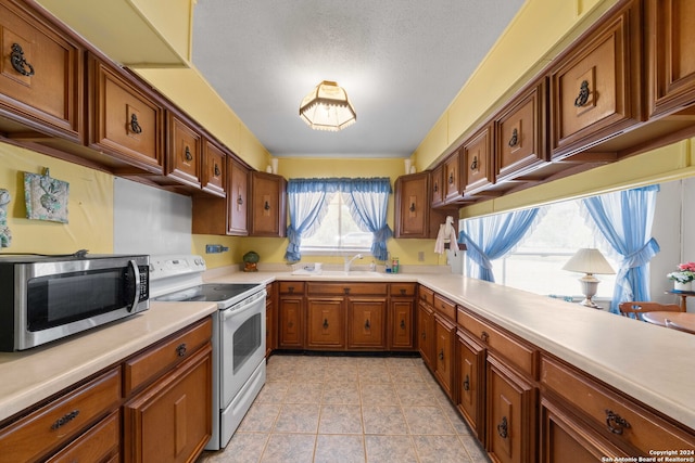 kitchen featuring sink, white range with electric stovetop, and light tile patterned floors