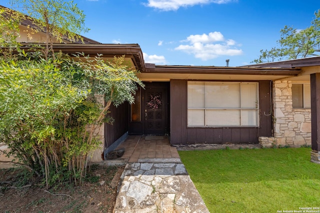 view of exterior entry featuring a lawn