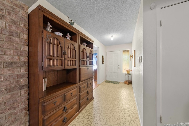 corridor with a textured ceiling and light tile patterned floors