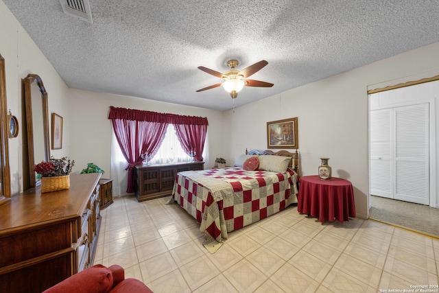 bedroom featuring ceiling fan, a closet, a textured ceiling, and light tile patterned flooring