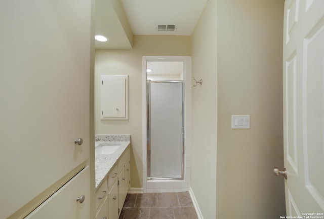 bathroom with tile patterned flooring, a shower with door, and vanity