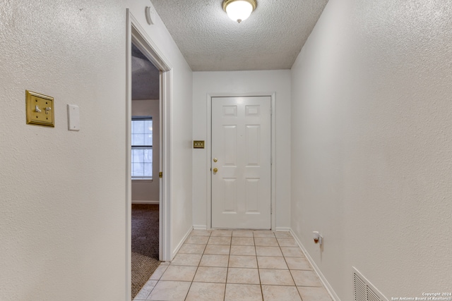 doorway featuring a textured ceiling and light tile patterned floors