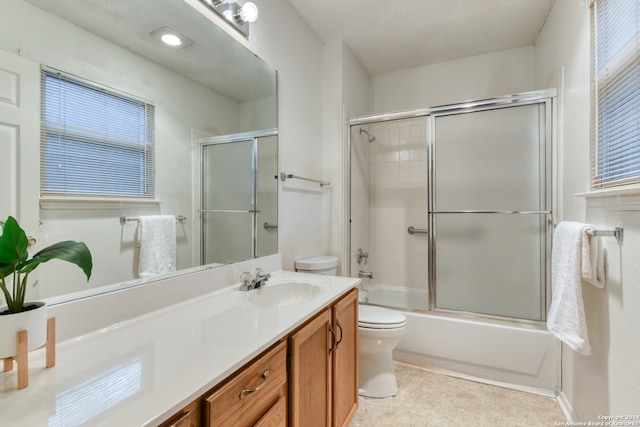 full bathroom with toilet, bath / shower combo with glass door, and vanity