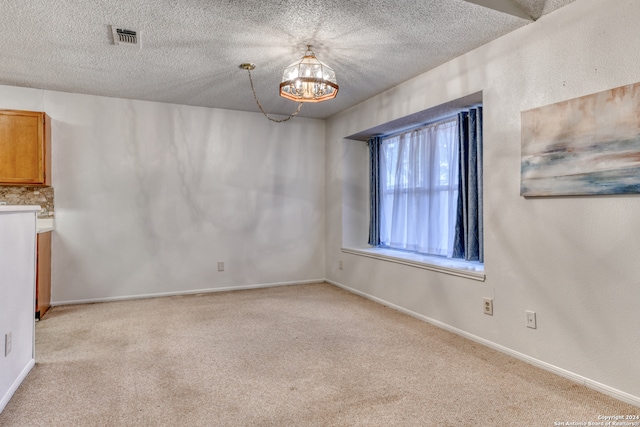 unfurnished room with light colored carpet, an inviting chandelier, and a textured ceiling