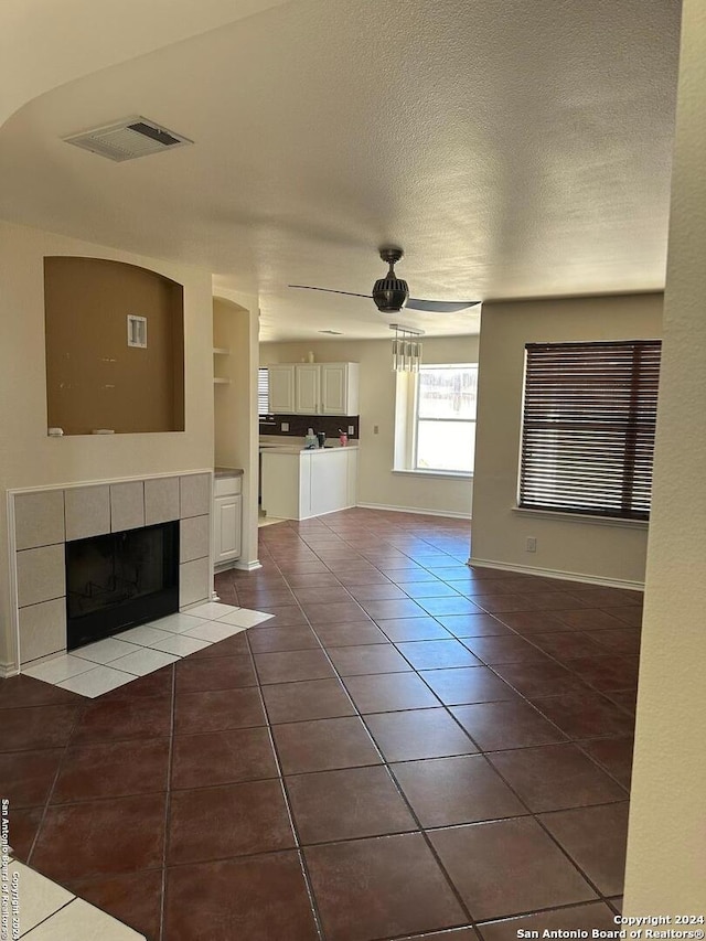 unfurnished living room with ceiling fan, tile patterned flooring, and a fireplace