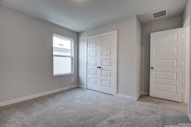 unfurnished bedroom featuring a closet and light colored carpet