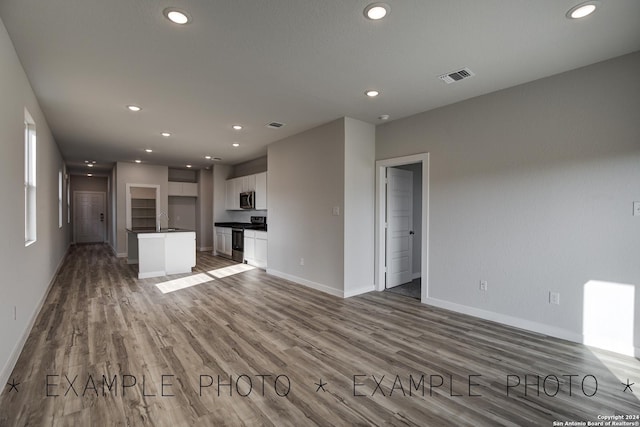 unfurnished living room featuring hardwood / wood-style floors and sink