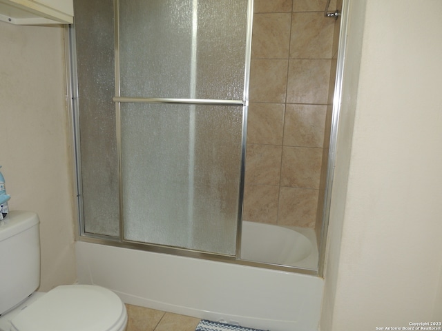 bathroom with shower / bath combination with glass door, toilet, and tile patterned floors