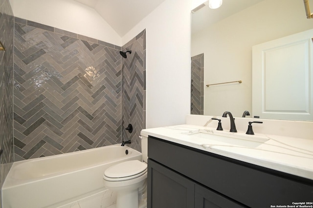 full bathroom featuring vanity, tiled shower / bath, toilet, and lofted ceiling