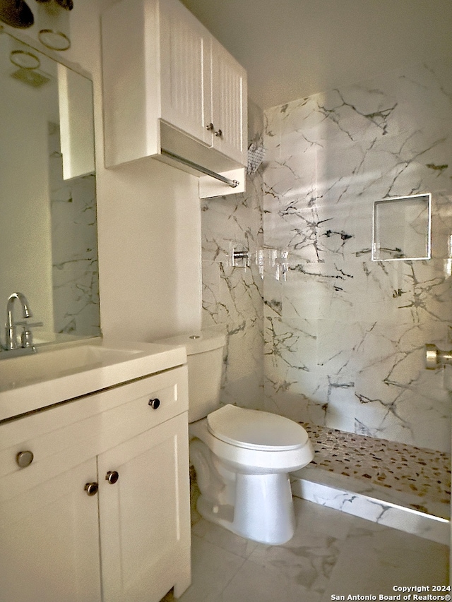 bathroom featuring tile patterned flooring, vanity, tiled shower, and toilet