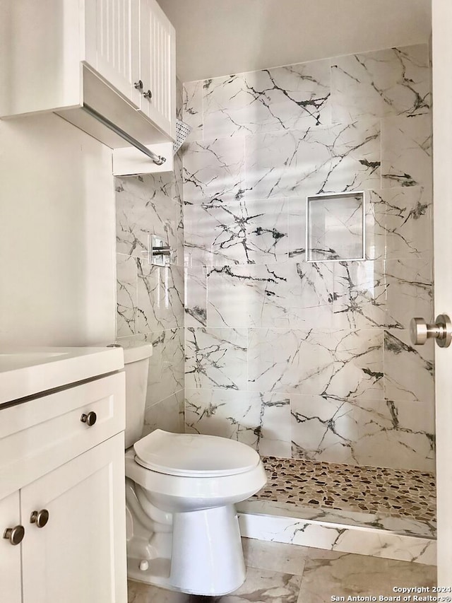 bathroom with tiled shower, tile patterned floors, vanity, tile walls, and toilet