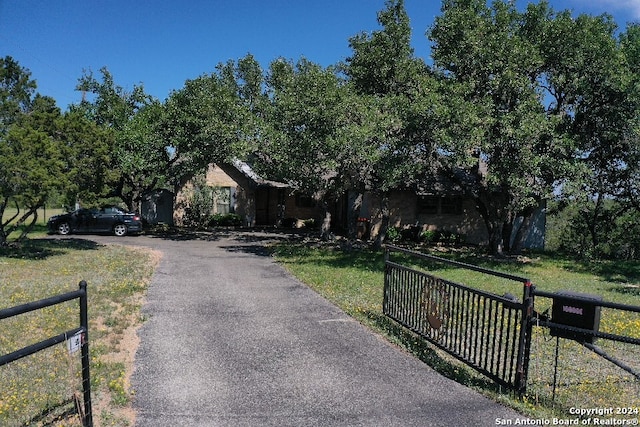 view of front of home featuring fence, a front lawn, and aphalt driveway