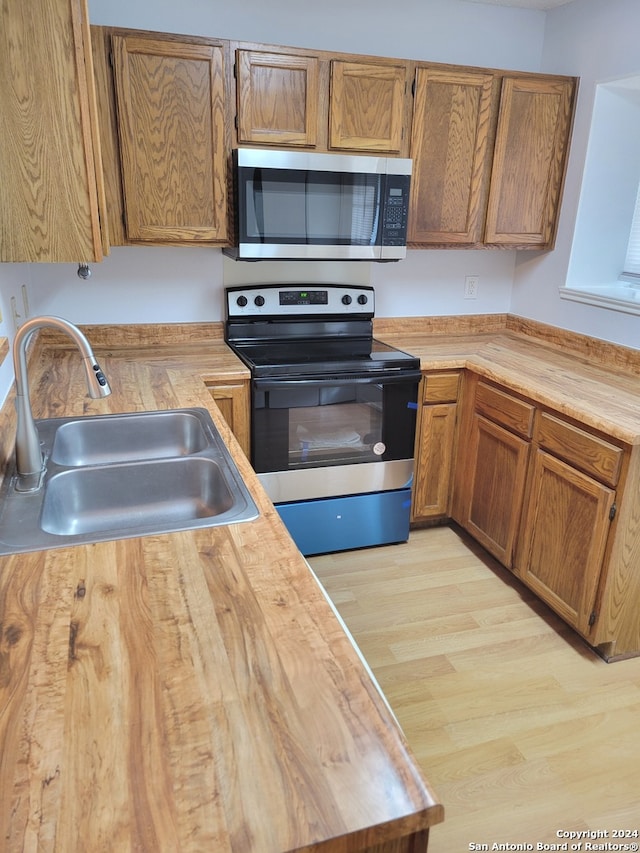 kitchen with light hardwood / wood-style floors, appliances with stainless steel finishes, sink, and wooden counters