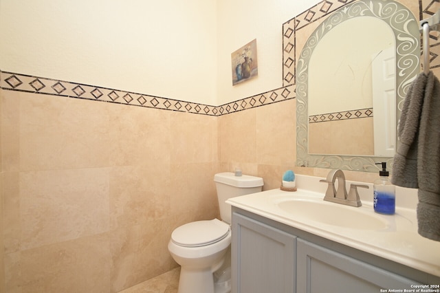 bathroom featuring tile walls, toilet, and vanity