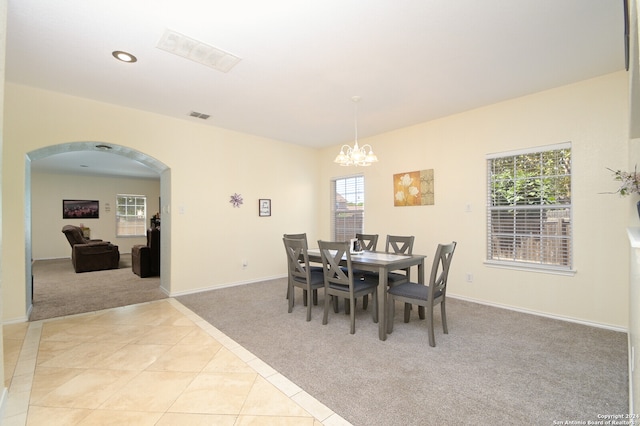 dining space with a wealth of natural light, light carpet, and a chandelier