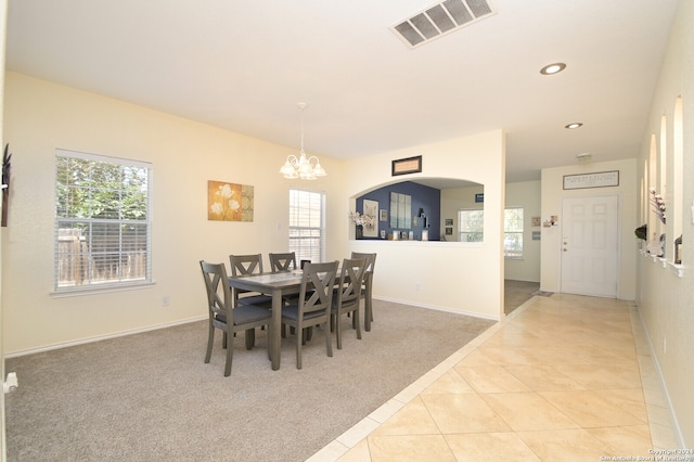 carpeted dining room featuring a notable chandelier