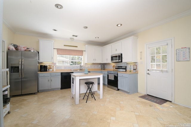 kitchen featuring appliances with stainless steel finishes, a kitchen island, a wealth of natural light, and backsplash