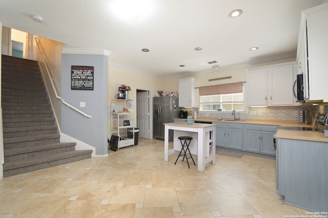 kitchen with stainless steel appliances, decorative backsplash, sink, a center island, and a breakfast bar