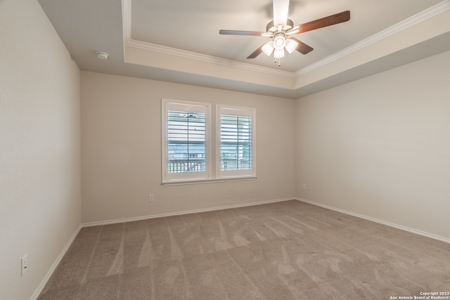 carpeted empty room featuring ceiling fan, a raised ceiling, and ornamental molding