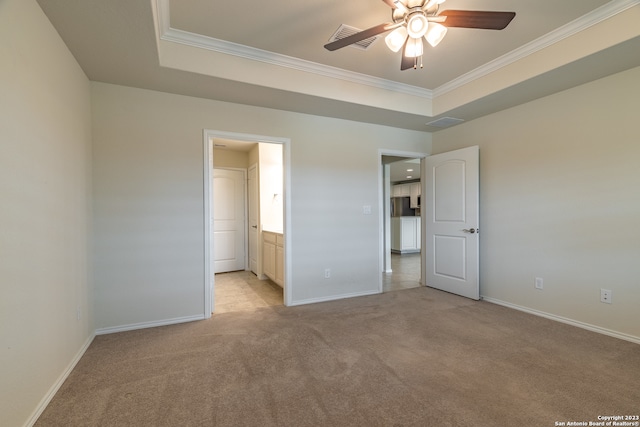 unfurnished bedroom with crown molding, ensuite bath, a tray ceiling, ceiling fan, and light carpet