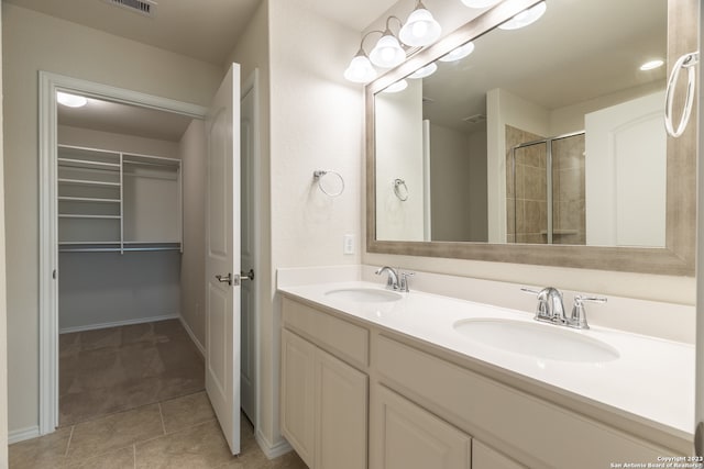 bathroom with a shower with door, double vanity, and tile patterned flooring