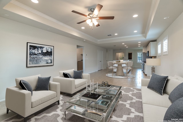 tiled living room featuring a tray ceiling, ceiling fan, and crown molding